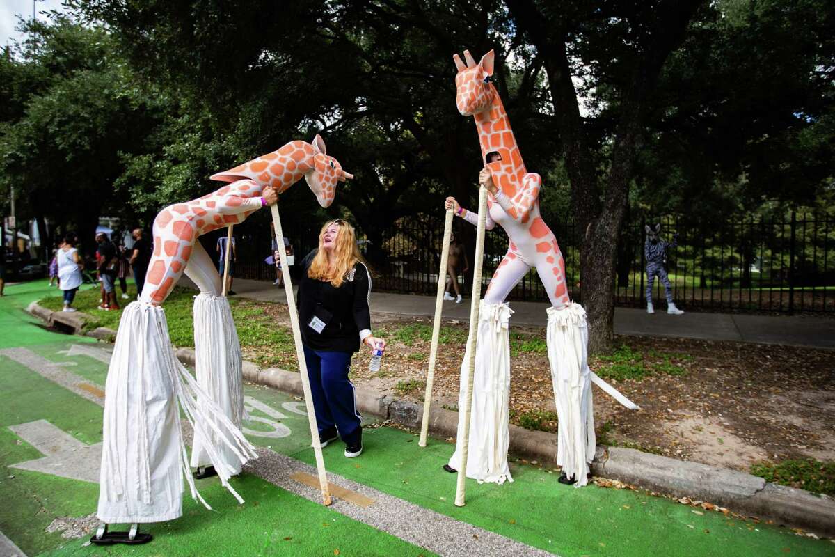 Sonia Guimbellot interacts playfully with Carver Aldine Dance Company dancers dressed as giraffes at the Bayou City Art Festival by the Sam Houston Park, Sunday, Oct. 10, 2021, in Houston.