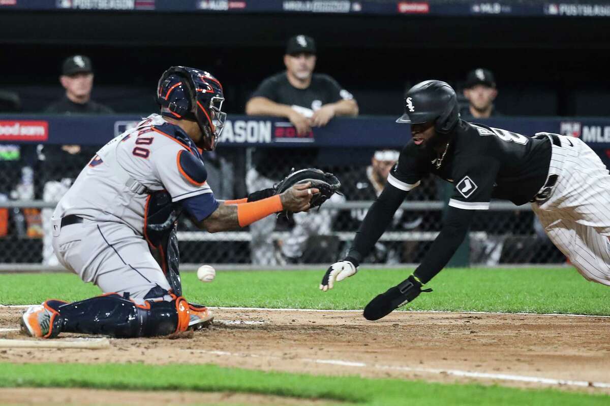 The ball gets past Houston Astros catcher Martin Maldonado (15) as Chicago White Sox center fielder Luis Robert (88) slides to score on a throwing error by first baseman Yuli Gurriel during the fourth inning in Game 3 of the American League Division Series Sunday, Oct. 10, 2021, in Chicago.
