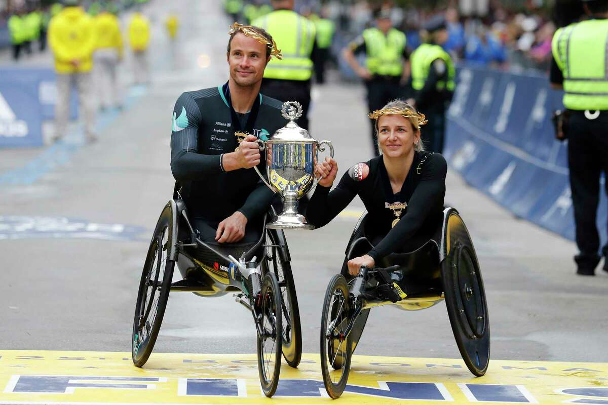 Marcel Hug, left, and Manuela Schar, both of Switzerland, celebrate after winning the wheelchair divisions of the 125th Boston Marathon on Monday, Oct. 11, 2021, in Boston.
