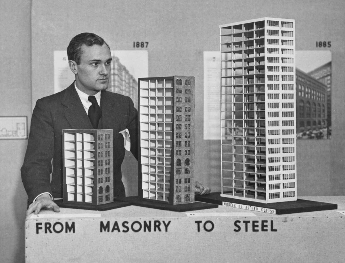 The American architect Philip Johnson (1906-2005), chairman of the architecture department of the Museum of Modern Art, with models that enable the development of building from the low, heavy dark masonry to the light, airy tower of modern architecture through steel frame construction, at an exhibition at Museum of Modern Art in New York City, New York, around 1932.