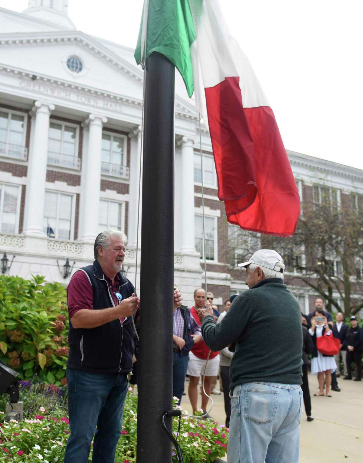 Tony DeVita Jr., left, and his father, Tony DeVita, raise the Italian flag during the 34th annual Columbus Day Celebration at Town Hall in Greenwich, Conn. Monday, Oct. 11, 2021. Presented by the St. Lawrence Society, the ceremony was dedicated to all members past and present for maintaining Italian traditions and heritage as the Italian flag was raised over Town Hall.