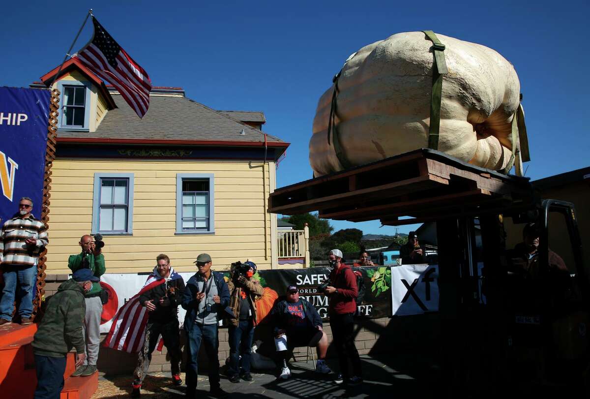 A pumpkin is transported to the scale to be weighed as people watch during the 48th Safeway World Championship Pumpkin Weigh-Off on Monday, October11,2021 in Half Moon Bay,, Calif.