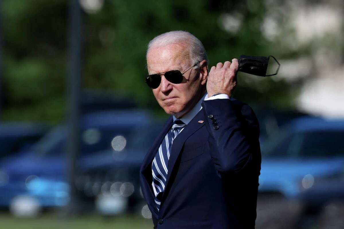 President Joe Biden removes his face mask as he walks to Marine One for a departure from the Ellipse near the White House on May 19 in Washington, D.C. Biden is traveling to New London, where he will deliver a keynote address during the United States Coast Guard Academy’s commencement ceremony.