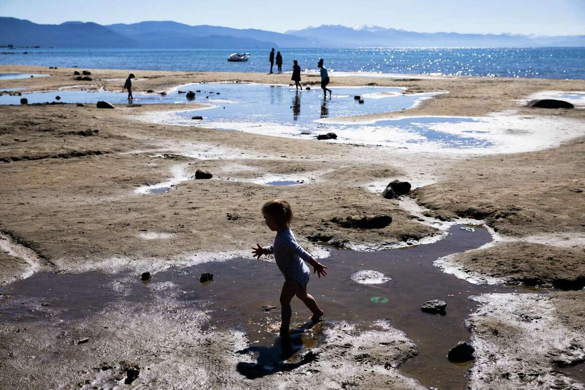Gov. Gavin Newsom says worsening California drought could call for mandatory water restrictions. Kids play on puddles left on an exposed lakebed at Kings Beach (Placer County) amid the worsening drought.