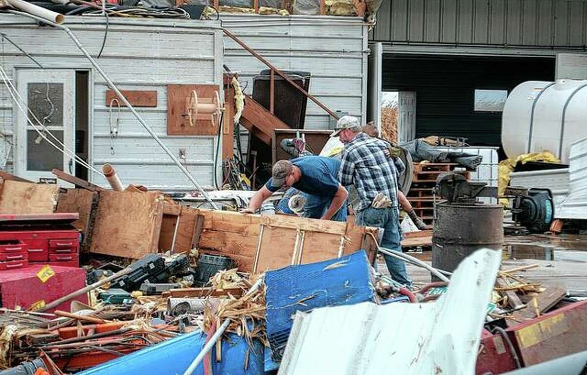 Property owner Scot Wright, left, rummages through items on his farm Monday afternoon after a tornado came through destroying sheds, a silo and farm equipment in Wrights in Greene County.