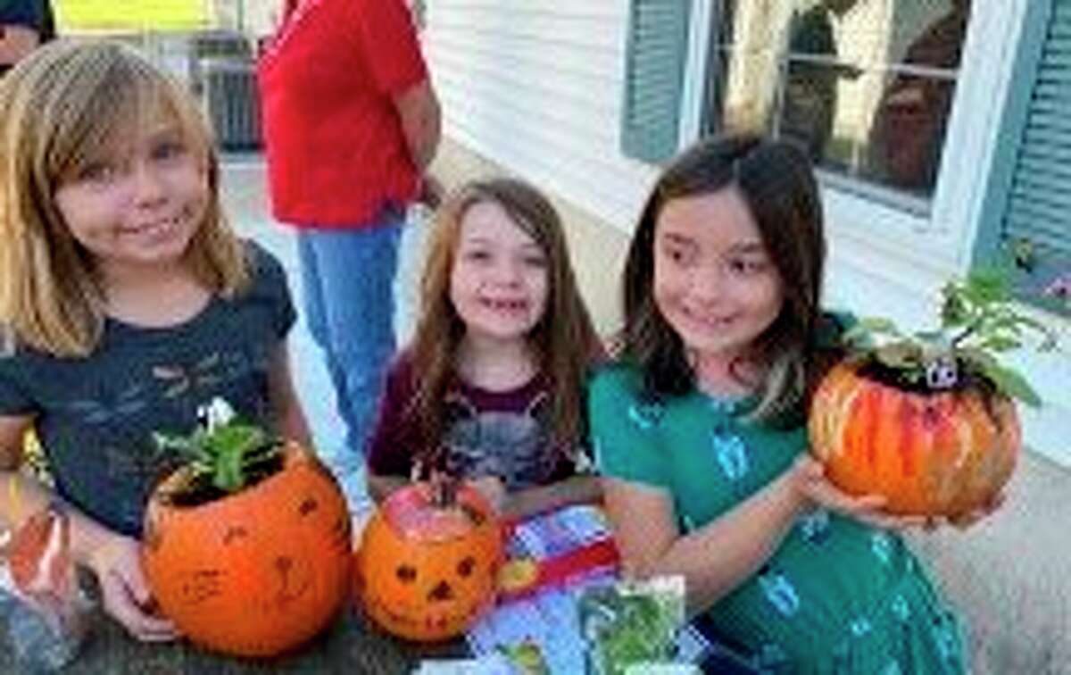 Josie Powell, Emma Powell  and Milaya Powell could be seen planting flowers inside of pumpkins during a recent  Spirit of the Woods Garden Club and Manistee County Library event. (Courtesy photo)