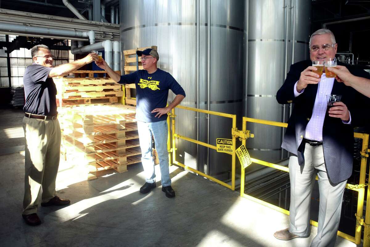 Master Brewer Phil Markowski, center, raises a toast as he leads a tour of the Two Roads Brewing Company brewery, in Stratford, Conn. Oct. 12, 2021. Markowski and Two Roads staff were joined by representatives from the University of Connecticut for the introduction of their new TwoConn Ale.