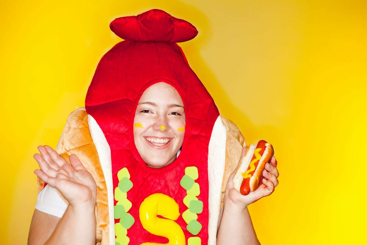 Woman in a hot dog costume holding a hot dog. 
