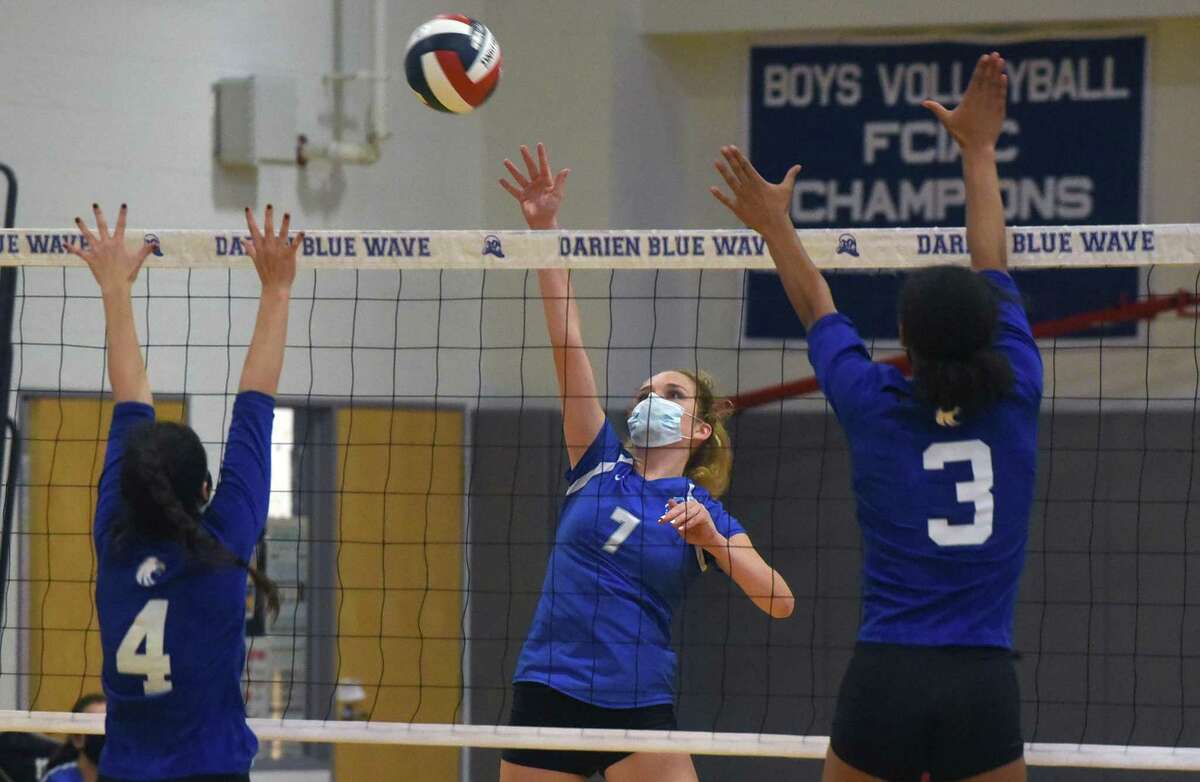 Darien's Jillian Roche (7) sends a shot over the net as Newtown's Lauren Young (4) and Keyera Smith (3) defend during a girls volleyball match in Darien on Monday, Sept. 13, 2021.