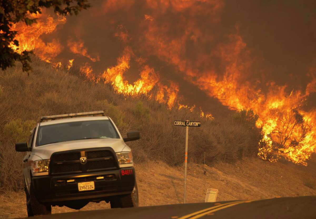 Flames from the Alisal Fire rise near firefighters in a pickup truck at Corral Canyon near Goleta, Calif.