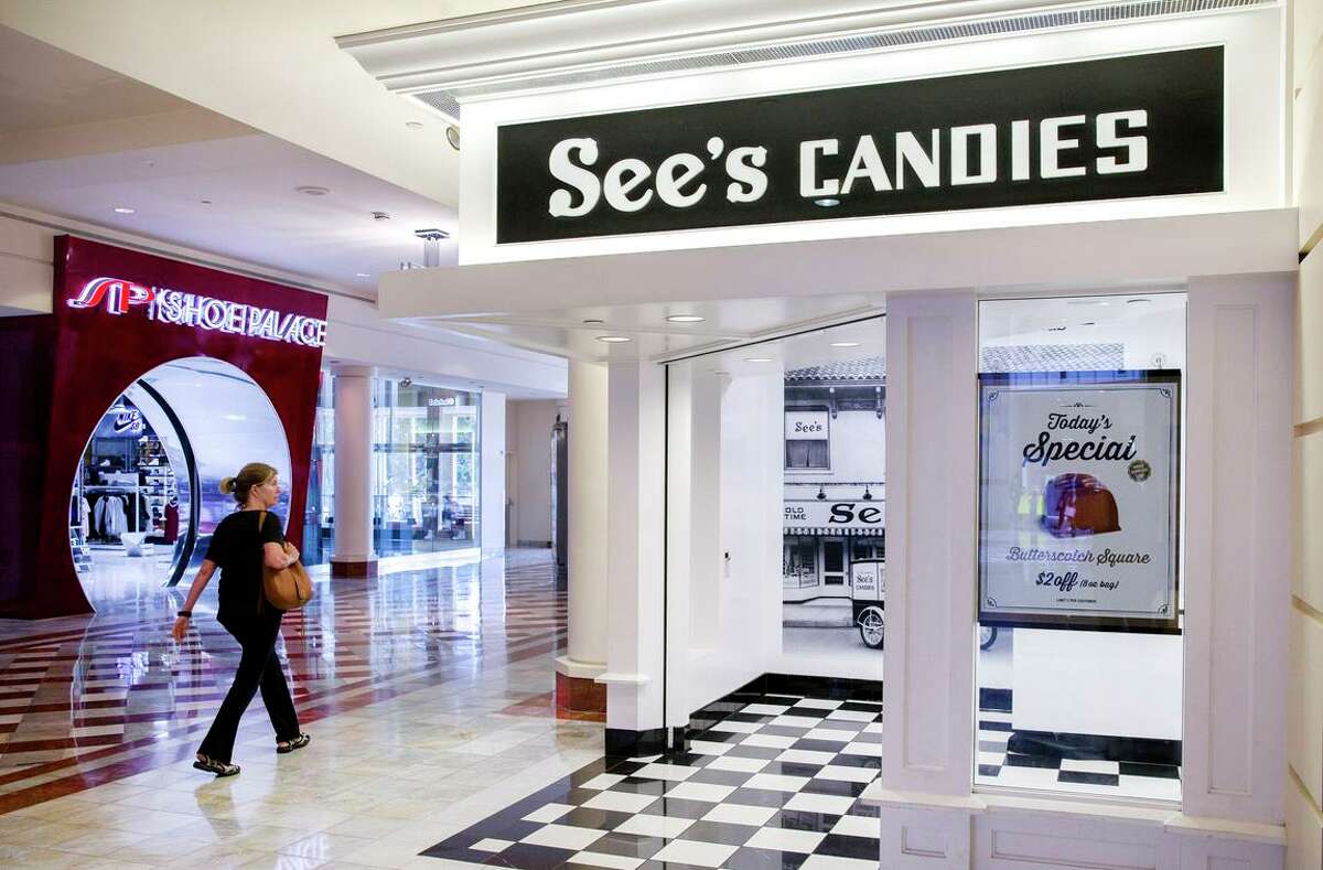 A woman walks past See's Candies inside the Stonestown Galleria on Aug. 1, 2017, in San Francisco, Calif. A state appeals court ruled Tuesday that the family of a man who died from COVID-19 that he caught from his wife, who was exposed at her job at a See’s Candy packing plant in Los Angeles County, can sue her employer for damages.