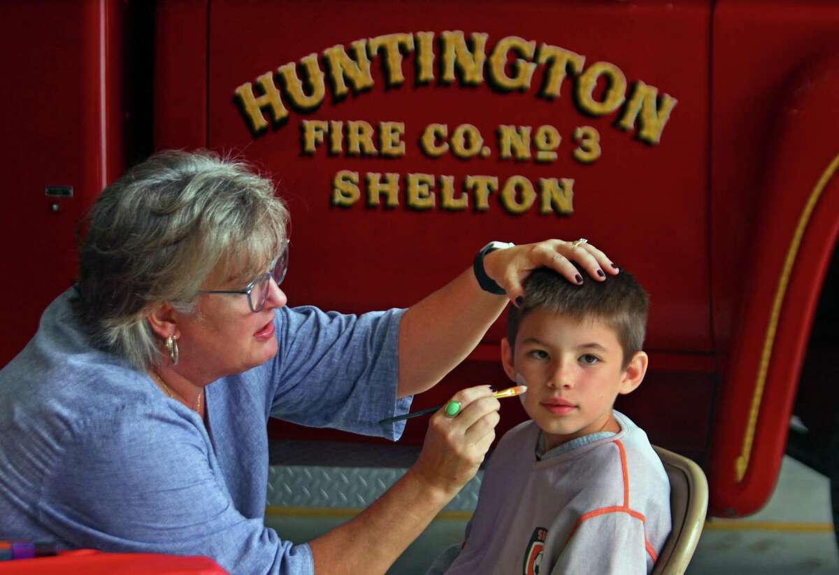 Andrew Fittante, 9, gets his face painted by Kelly McClinch Pineau.