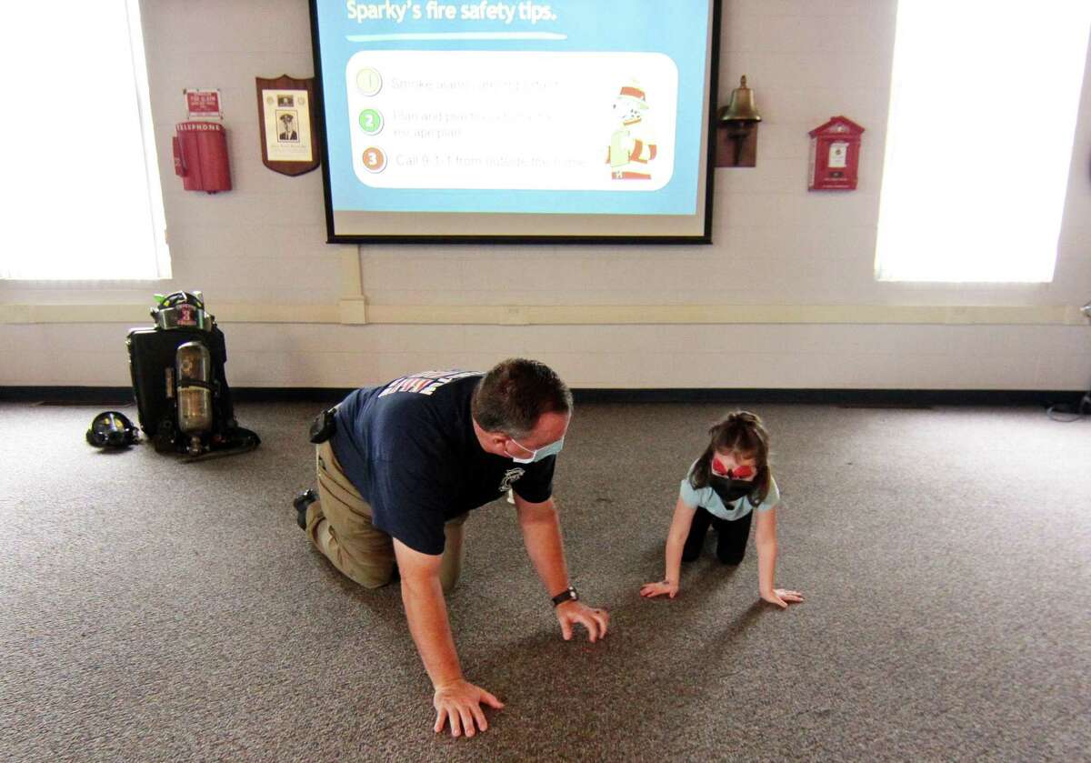 Huntington Fire Company No. 3 firefighter Jeff Daniels teaches MacKenzie Lougal, 4, to "Get down and get out!" drill in case of a fire at home during the department's first ever fire prevention event in on Saturday.