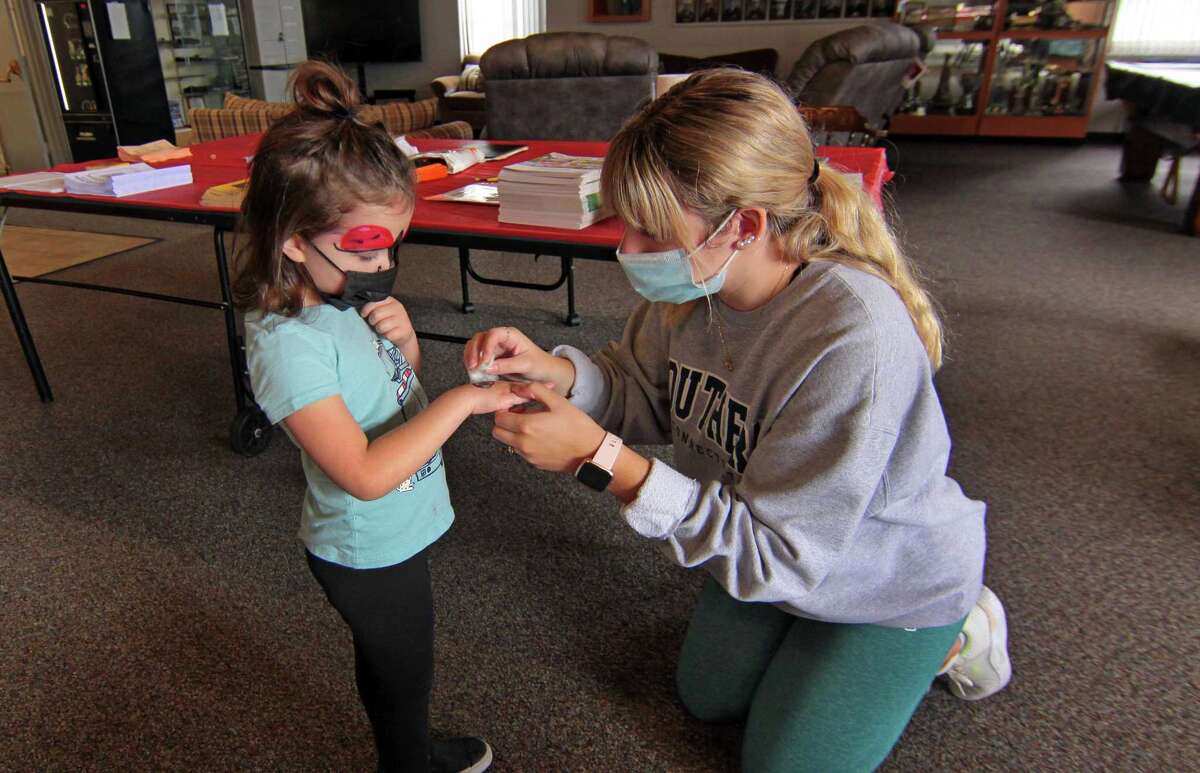 Volunteer Caitlin Foothorap applies a temporary tattoo for MacKenzie Lougal, 4, during Huntington Fire Company No. 3's first ever fire prevention event in Shelton, Conn., on Saturday October 9, 2021. A variety of activities were available for kids to take part in. Kids learned valuable fire safety tips from department firefighters, got a close up view of life-saving equipment and face paintings to name just a few.