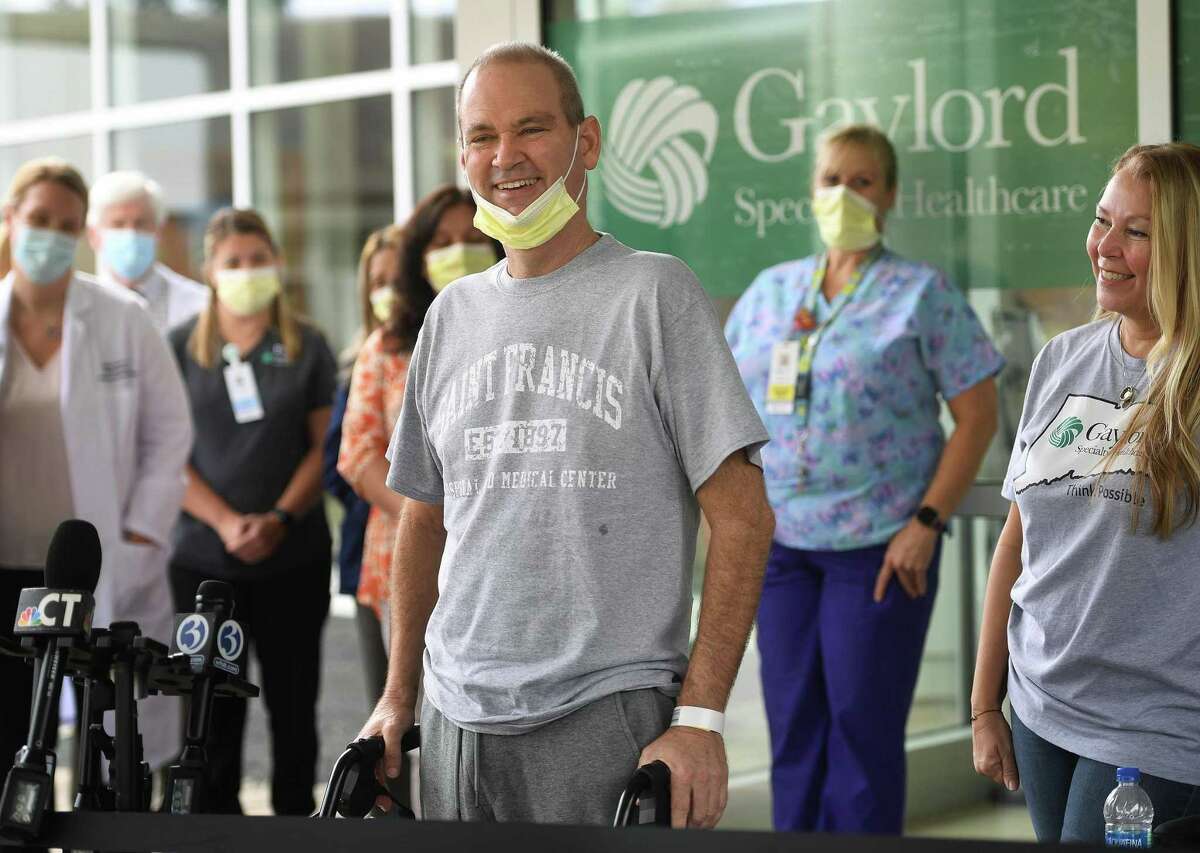 Florida resident Robby Walker smiles as he leaves Gaylord Hospital Wednesday after receiving Covid-19 treatment . in Wallingford, Conn. on Wednesday, October 13, 2021. Walker received ECMO treatment at St. Francis Hospital in Hartford, where the patient's blood is oxygenated outside the body to help the lungs in recovery. At right is Walker's wife, Susan Walker, who's plea on CNN lead to her husband's treatment in Connecticut.