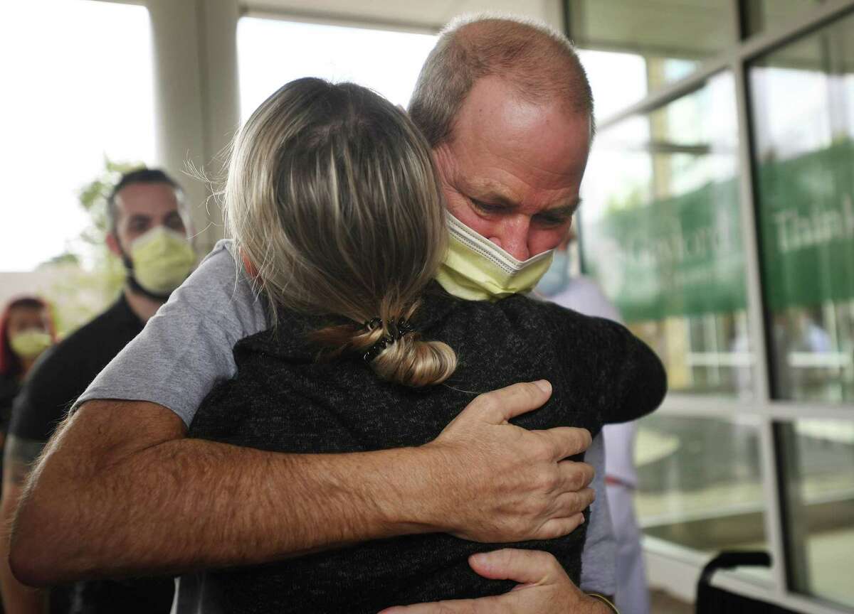 Florida resident Robby Walker hugs medical staff, left; at right, the staff applauds him as he is released. during his release from Gaylord Hospital and Covid-19 treatment in Wallingford, Conn. on Wednesday, October 13, 2021. Walker received ECMO treatment at St. Francis Hospital in Hartford, where the patient's blood is oxygenated outside the body to help the lungs in recovery.