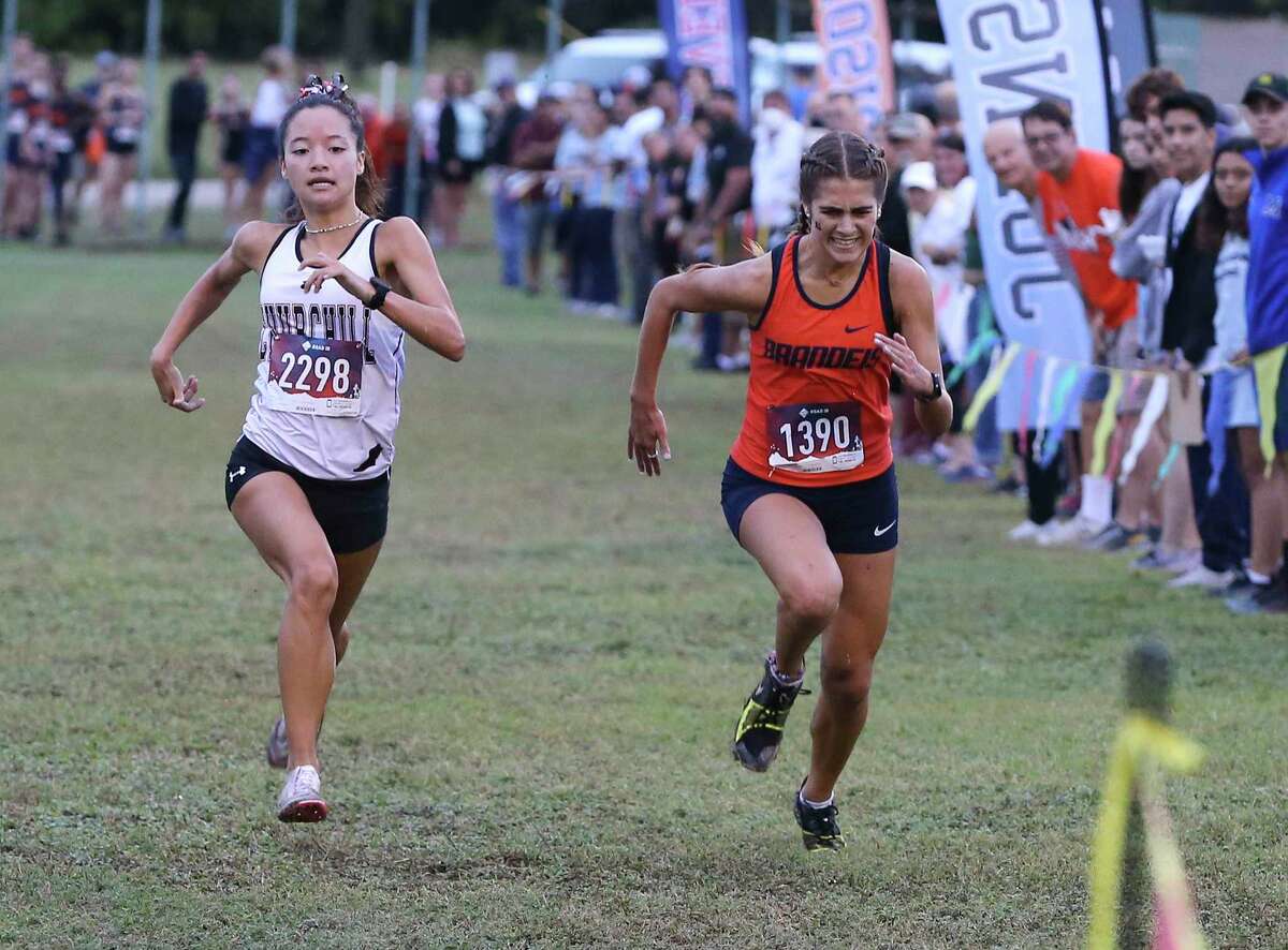 Churchill's Ashley Moore (left) beats out Brandeis' Mikaela Garza as they finish second and third respectively in the District 28-6A cross country championships at North East Sports Park on Thursday, Oct. 14, 2021.