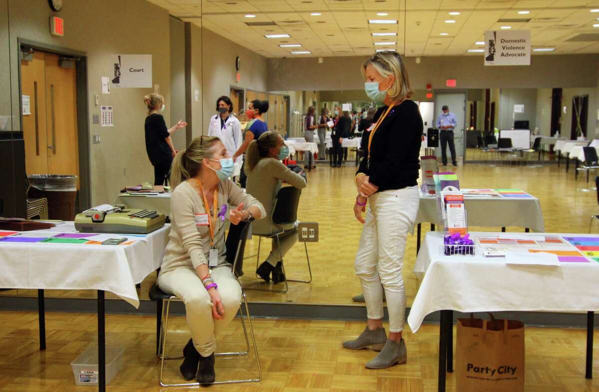 Anne Birchenough, left, and Colleen Hines, with YWCA Greenwich's Domestic Abuse Services, chat before the start of the In Their Shoes event to mark Domestic Violence Awareness Month in Greenwich, Conn., on Wednesday October 13, 2021. The event allows people to walk in the shoes of people experiencing abusive and controlling relationships. Attendees paired up and each chose a colored card, which took them to various stations set up to represent scenarios that victims of domestic abuse go through, like child custody, an abuse shelter, therapy or court, among others.