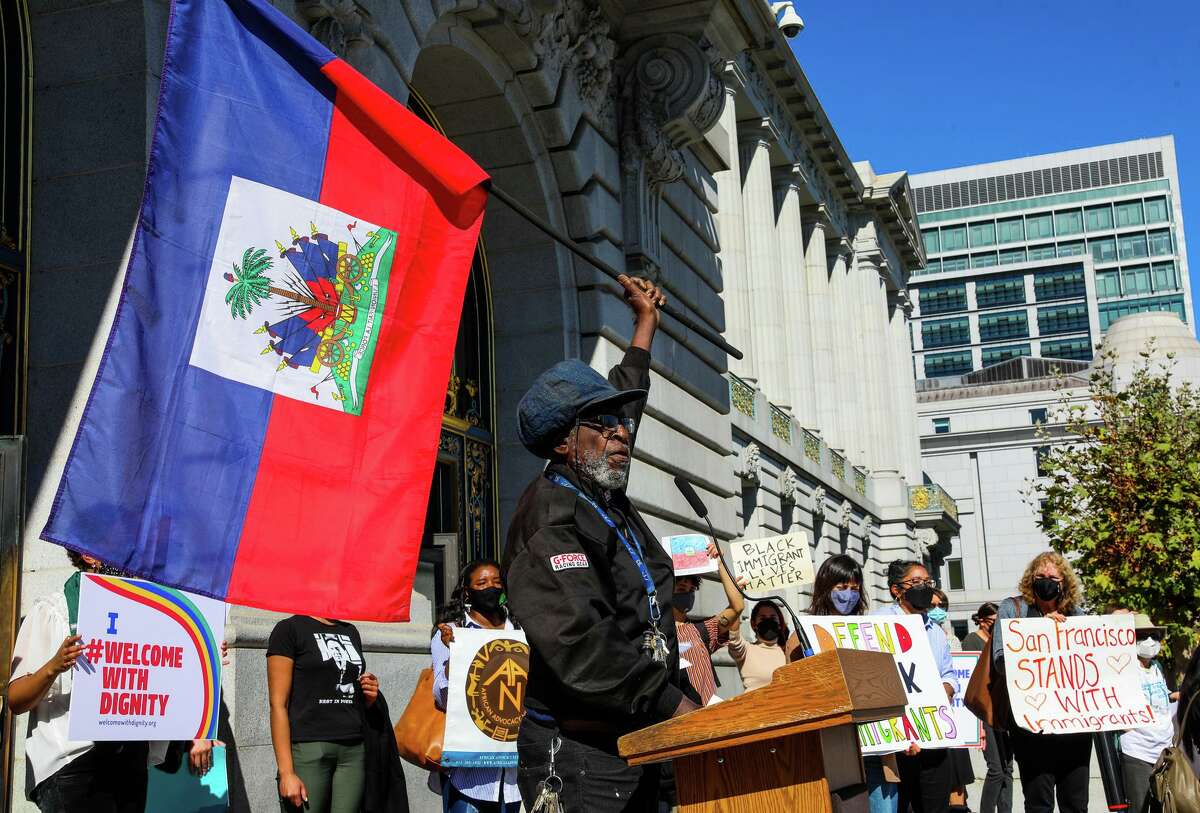 Ustadi Kadiri, with the Haiti Action Committee, holds an Haitian flag while criticizing the expulsion of Haitian asylum seekers from the U.S. during a rally in front of San Francisco City Hall on Thursday, Oct. 14, 2021.