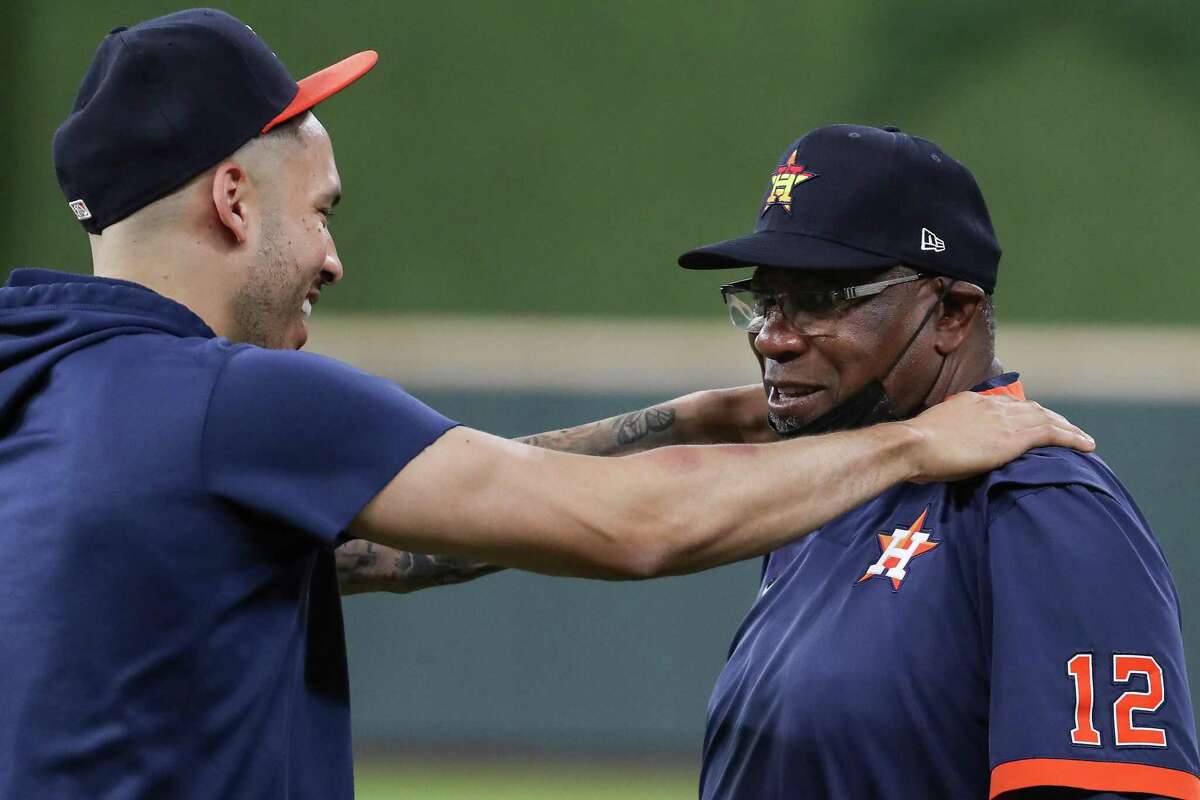 Houston Astros shortstop Carlos Correa, left, and manager Dusty Baker Jr. interact on the field during a workout the day before Game 1 of the American League Championship Series against the Boston Red Sox Thursday, Oct. 14, 2021 in Houston.