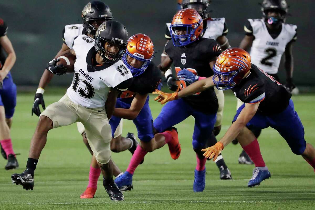 Conroe running back Nigel Leday (13) breaks the tackle attempts by Grand Oaks defends, from left, Max Magsingit,Lonnie Johnson and Tristian Frazier during the first half of their 13-6A district high school football game at Woodforest Bank Stadium Thursday, Oct. 14, 2021 in Shenandoah, TX.