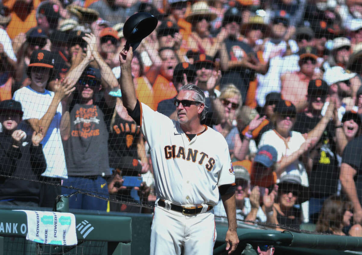 San Francisco Giants third-base coach Ron Wotus raises his hat to fans during his last game with the Giants.