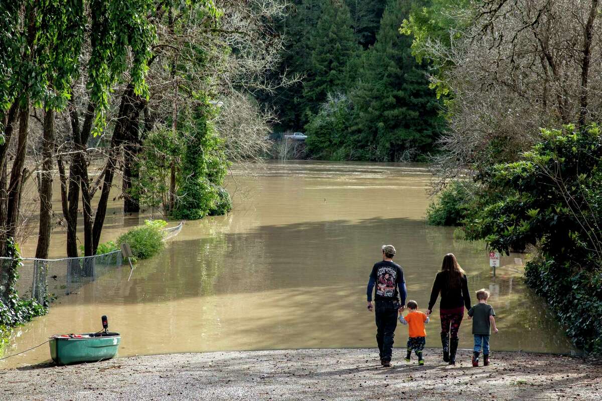 A family checks out the flooded Johnson’s Beach from Church Street in Guerneville in January 2017.