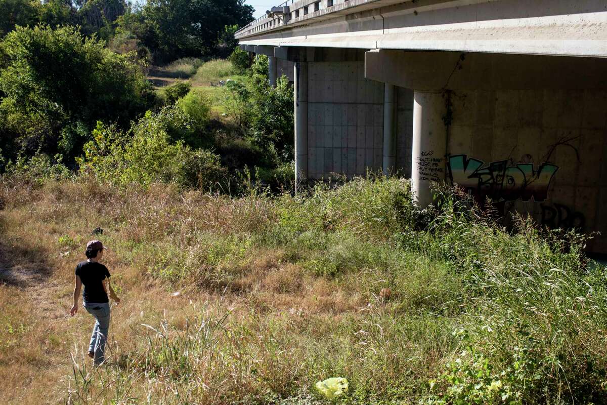 In this file photo from Sept. 21, 2021, Hannah Durrance, founder of the nonprofit HOME Center, which helps people experiencing homelessness in the city of San Marcos, makes her way under a bridge to check for campers after a rumored crackdown caused many to flee their makeshift homes.