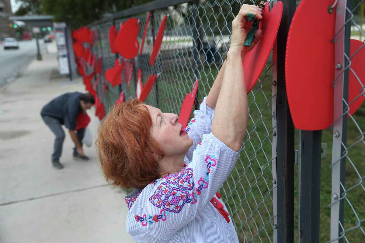 Rev. Wyndee Holbrook, 62, joins other volunteers in removing hearts that make up a COVID-19 memorial on a fence at by the Henry B. Gonzalez Convention Center on Friday. The city of San Antonio has decided to remove a memorial to COVID-19 victims at the intersection of Market and South Alamo Streets to make way for the construction of a new park. Since the memorial’s dedication in May 2021, residents have affixed more than 3,400 hearts, each meant to symbolize a victim of COVID-19, to a chain-link fence. Hearts with personal messages will be archived and the blank ones will be used by children in the Head Start program as art projects.