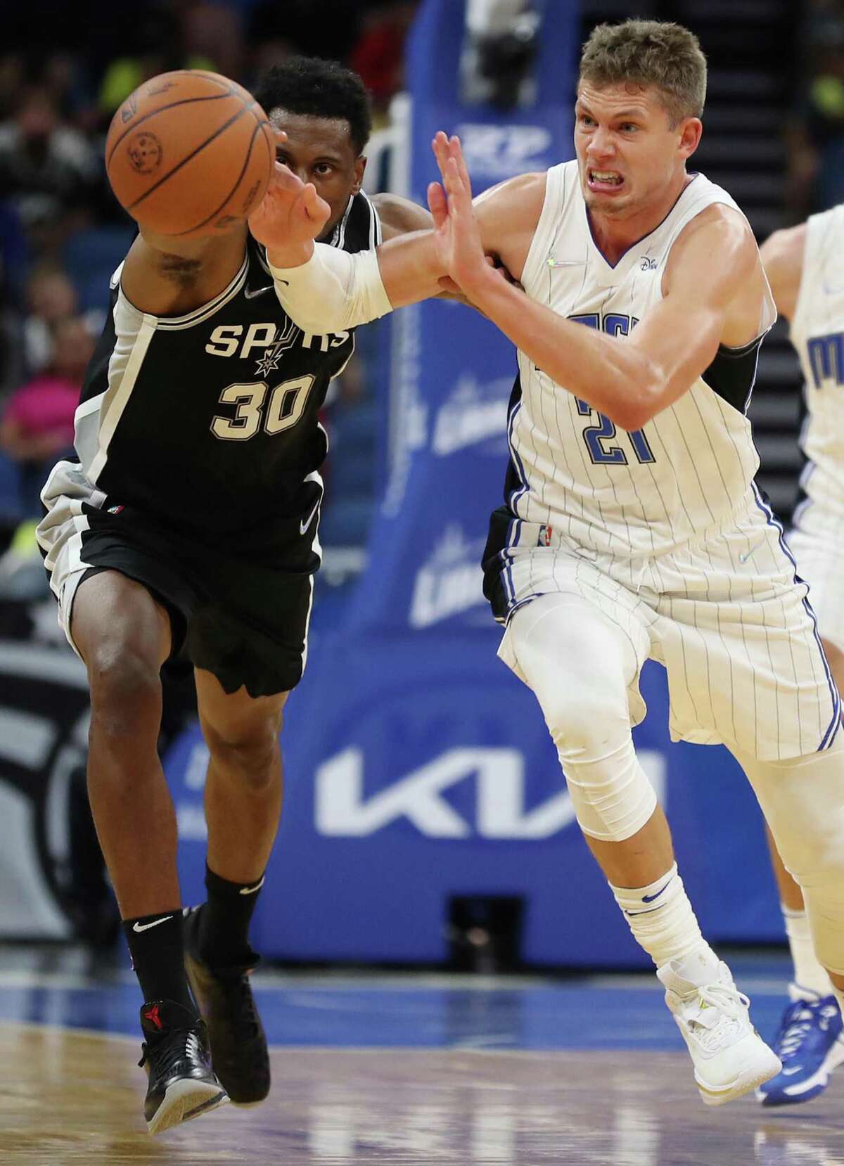 Orlando Magic center Moritz Wagner (21) and San Antonio Spurs forward Thaddeus Young (30) chase the ball during a preseason game at the Amway Center on Sunday, Oct. 10, 2021 in Orlando, Florida. San Antonio won the game 101-100. (Stephen M. Dowell/Orlando Sentinel/TNS)