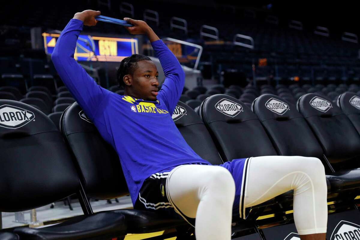 Golden State Warriors' Jonathan Kuminga sits after warming up before playing Denver Nuggets during NBA preseason game at Chase Center in San Francisco, Calif., on Wednesday, October 6, 2021.