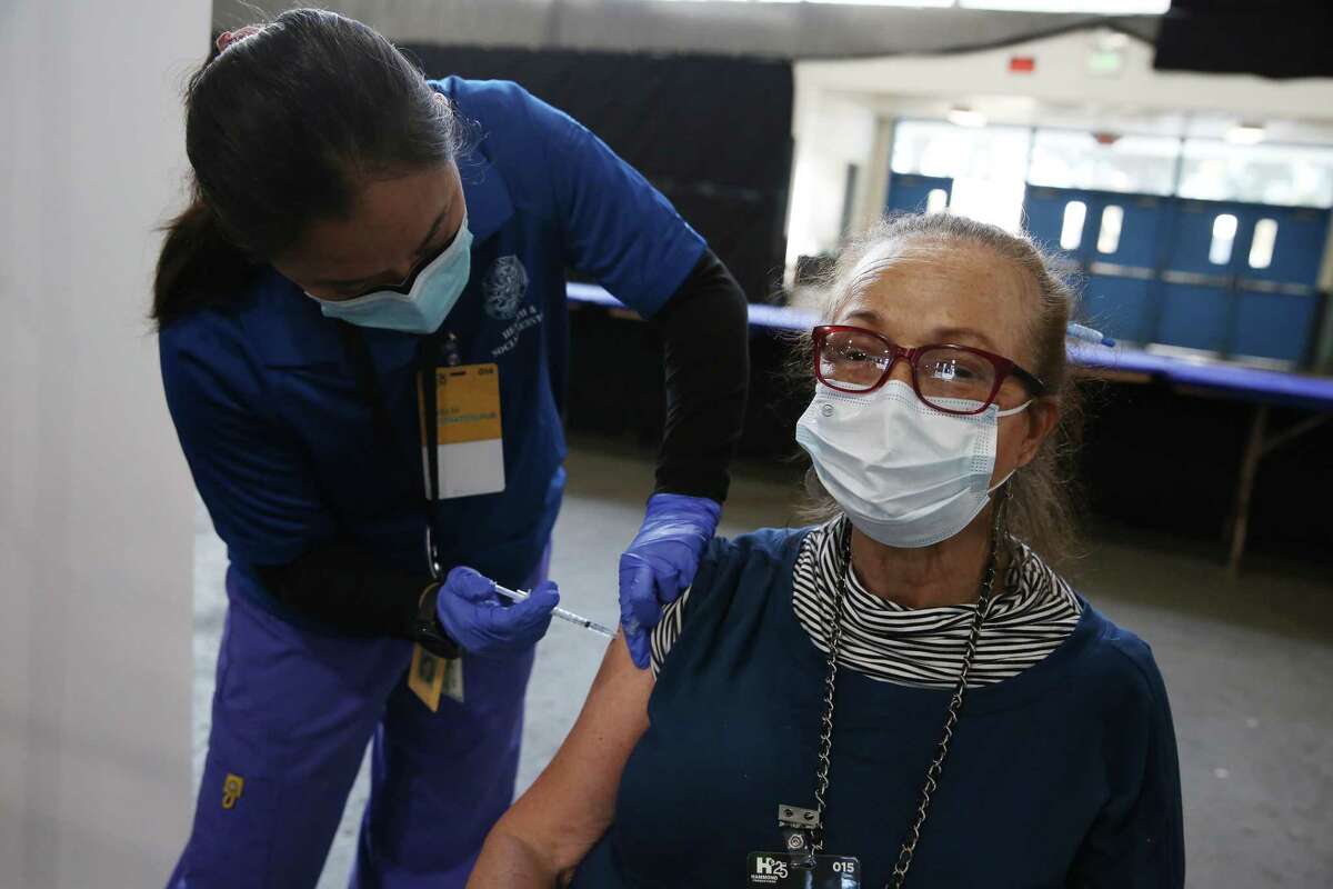 Dennise Carignan (right) of Napa receives her Pfizer booster vaccine from public health nurse Mariejoy Supapo at the mass vaccination site at the Solano County Fairgrounds on Wednesday, October 13, 2021 in Vacaville, Calif.