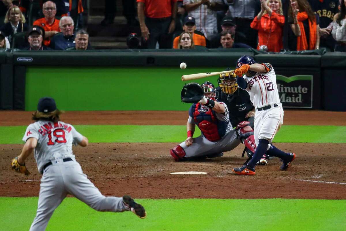 Houston Astros second baseman Jose Altuve (27) hits a sacrifice fly that scores Houston Astros first baseman Yuli Gurriel (10) and gave the Astros a 5-3 lead during the eighth inning in Game 1 of the American League Championship Series on Friday, Oct. 15, 2021, at Minute Maid Park in Houston.