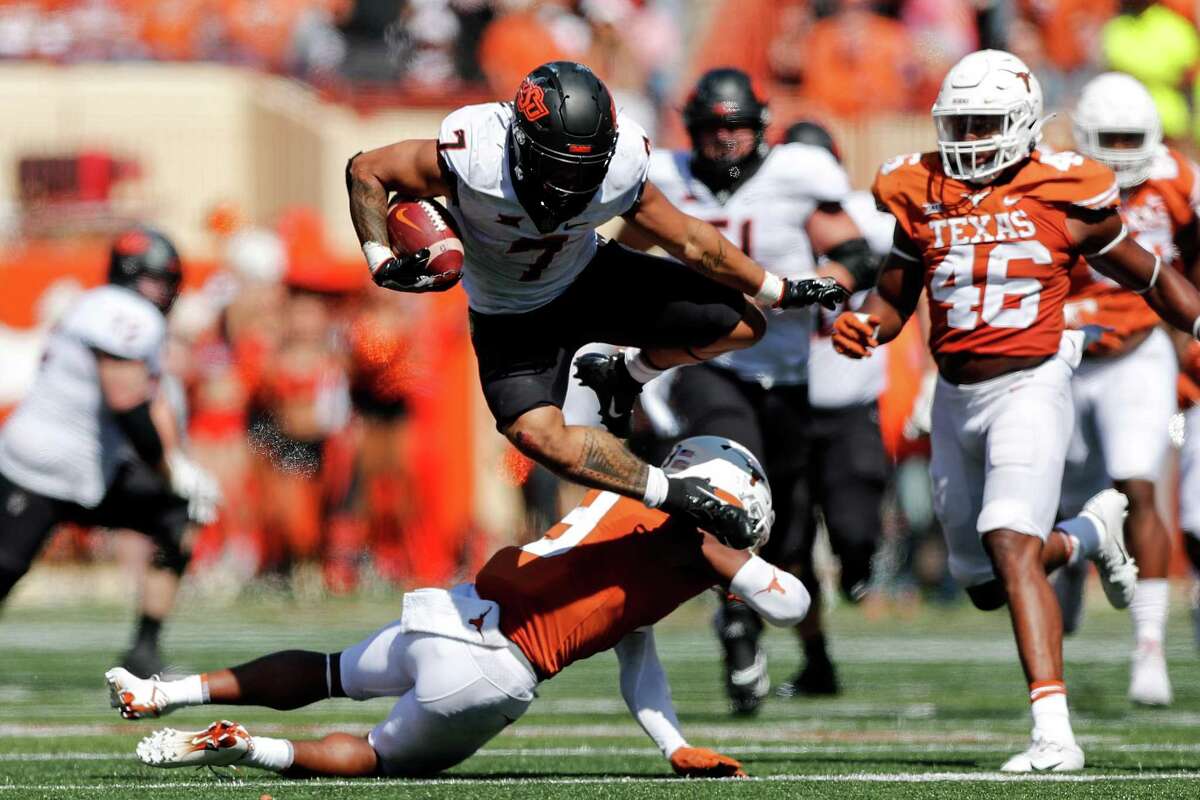 Oklahoma State’s Jaylen Warren hurdles Josh Thompson of the Texas during a fourth-quarter run. Warren finished with 193 yards rushing on 33 carries.