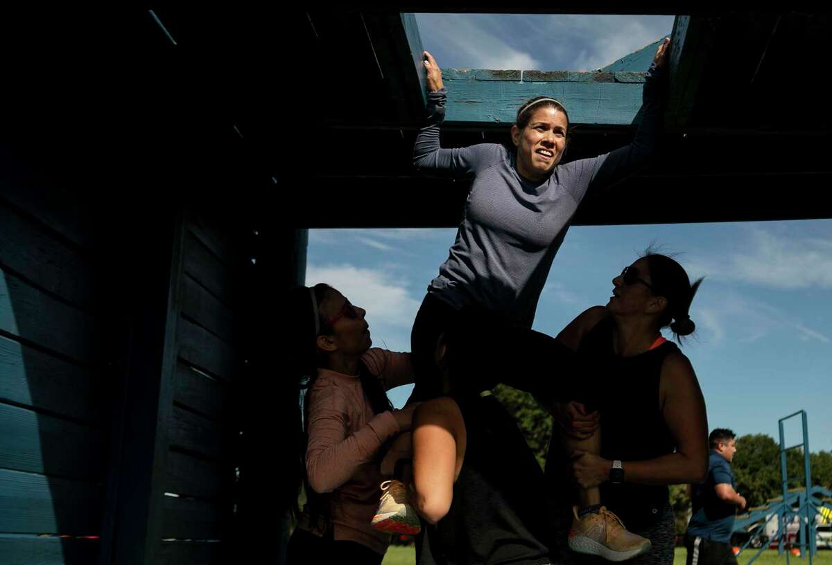 Jenifer Flores grimaces as she works with her team to complete the San Antonio Police Department SWAT Challenge on Saturday.