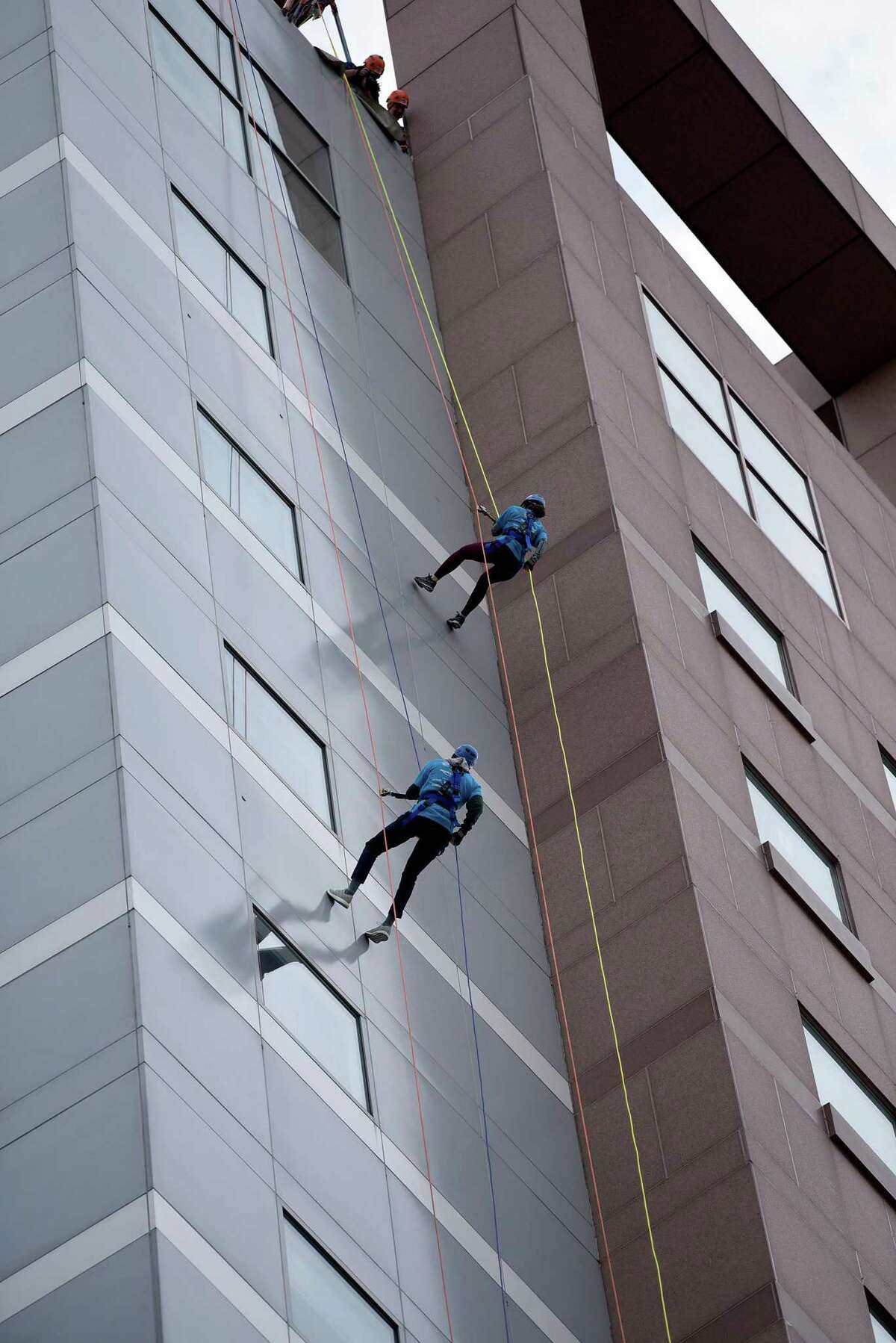 Two friends, John Guzzi, left, and Nadeen Hussain, both 28, from Milford, rappel from the top of the People’s United Bank building.