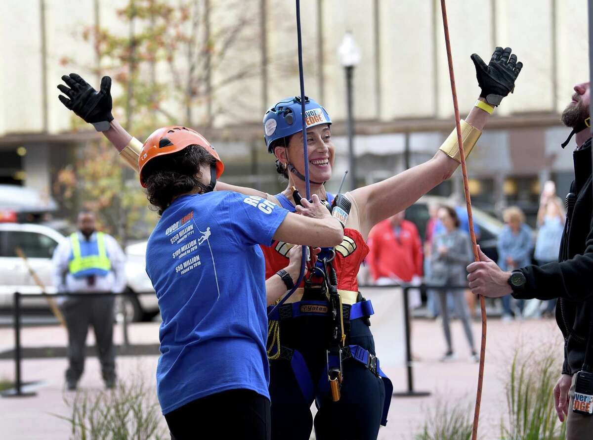 Andrea Kovacs of Bridgeport is unharnessed by Elena Simoes after completing her turn at rapelling off the People’s United Bank building in Bridgeport Saturday, Oct. 16, 2021. The event was a fundraising effort for Wakeman’s Boys and Girls Club in Southport. It was held in conjunction with Over the Edge.