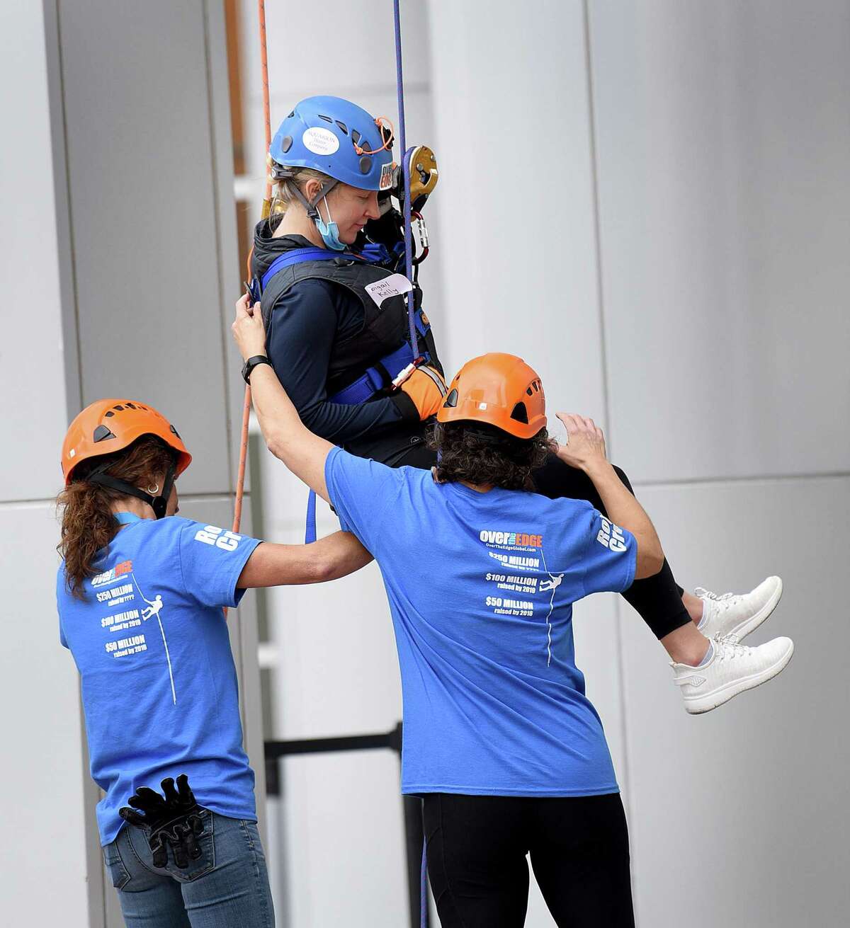 Abigail Kelly is helped to land by Karen Sirois, left, and Elena Simoes, volunteers from Wakeman’s Boys and Girls Club. As a fundraising effort for Wakeman’s Boys and Girls Club in Southport, people rappelled down the People’s United Bank building in Bridgeport Saturday, Oct. 16, 2021. The event was held in conjunction with Over the Edge.