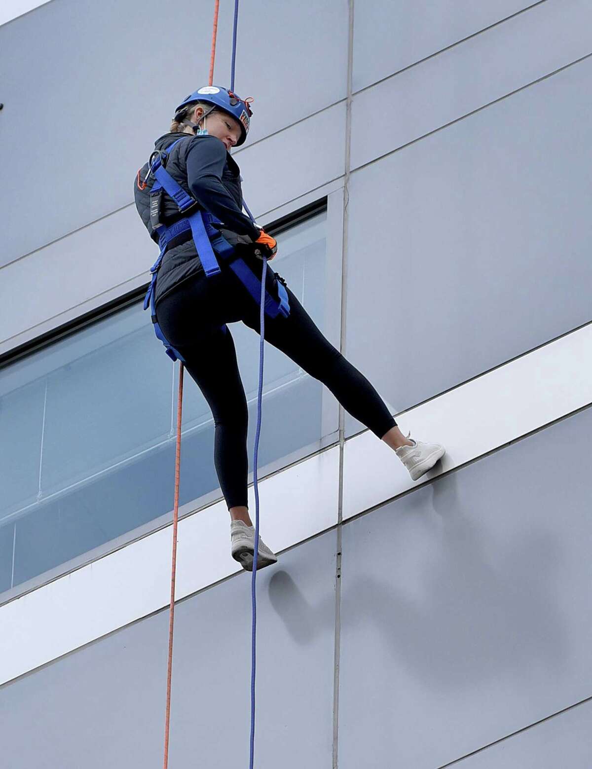 Abigail Kelly rapells from the top of the People’s United Bank building in downtown Bridgeport, Saturday, Oct. 16, 2021. The event was a fundraising effort for Wakeman’s Boys and Girls Club in Southport held in conjunction with Over the Edge.