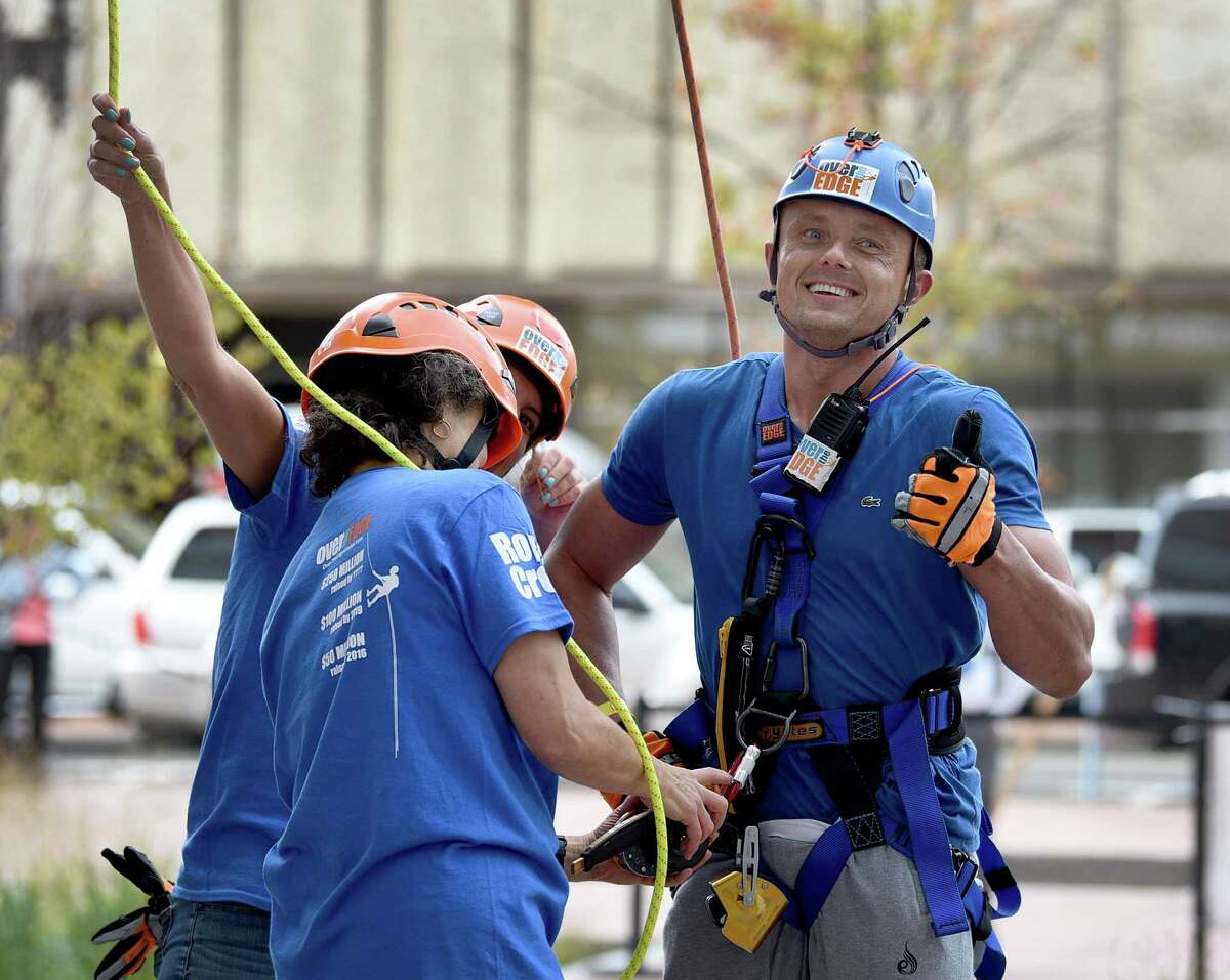 Jeff Webster gives a thumbs up to supporters after completing his descent from the top of the People’s United Bank building in Bridgeport, Saturday, Oct. 16, 2021. In a fundraising effort for Wakeman’s Boys and Girls Club in Southport, people rappelled down the People’s United Bank building in Bridgeport Saturday, Oct. 16, 2021. The event was held in conjunction with Over the Edge.