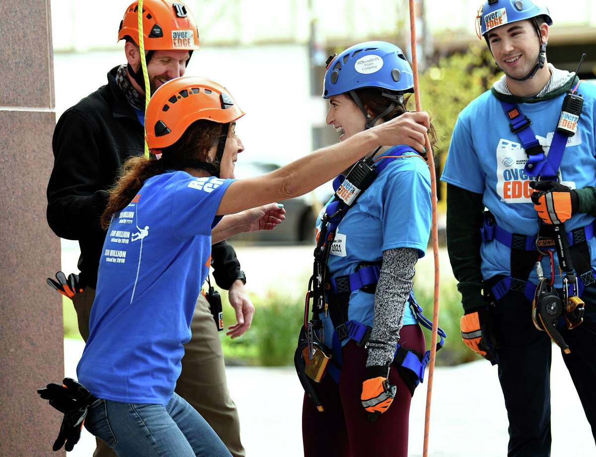 Nadeen Hussain, center, is congratulated by Karen Sirois, a volunteer with Wakeman Boys and Girls Club. Hussain had just completed her first time rappelling from a building. In a fundraising effort for Wakeman’s Boys and Girls Club in Southport, people rappelled down the People’s United Bank building in Bridgeport Saturday, Oct. 16, 2021. The event was held in conjunction with Over the Edge.