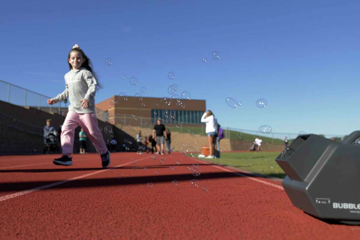A walker runs through bubbles on the track during the first Montgomery ISD Walkathon for Hunger held at the Montgomery Jr. High School track Saturday, Oct. 16, 2021 in Montgomery, TX.