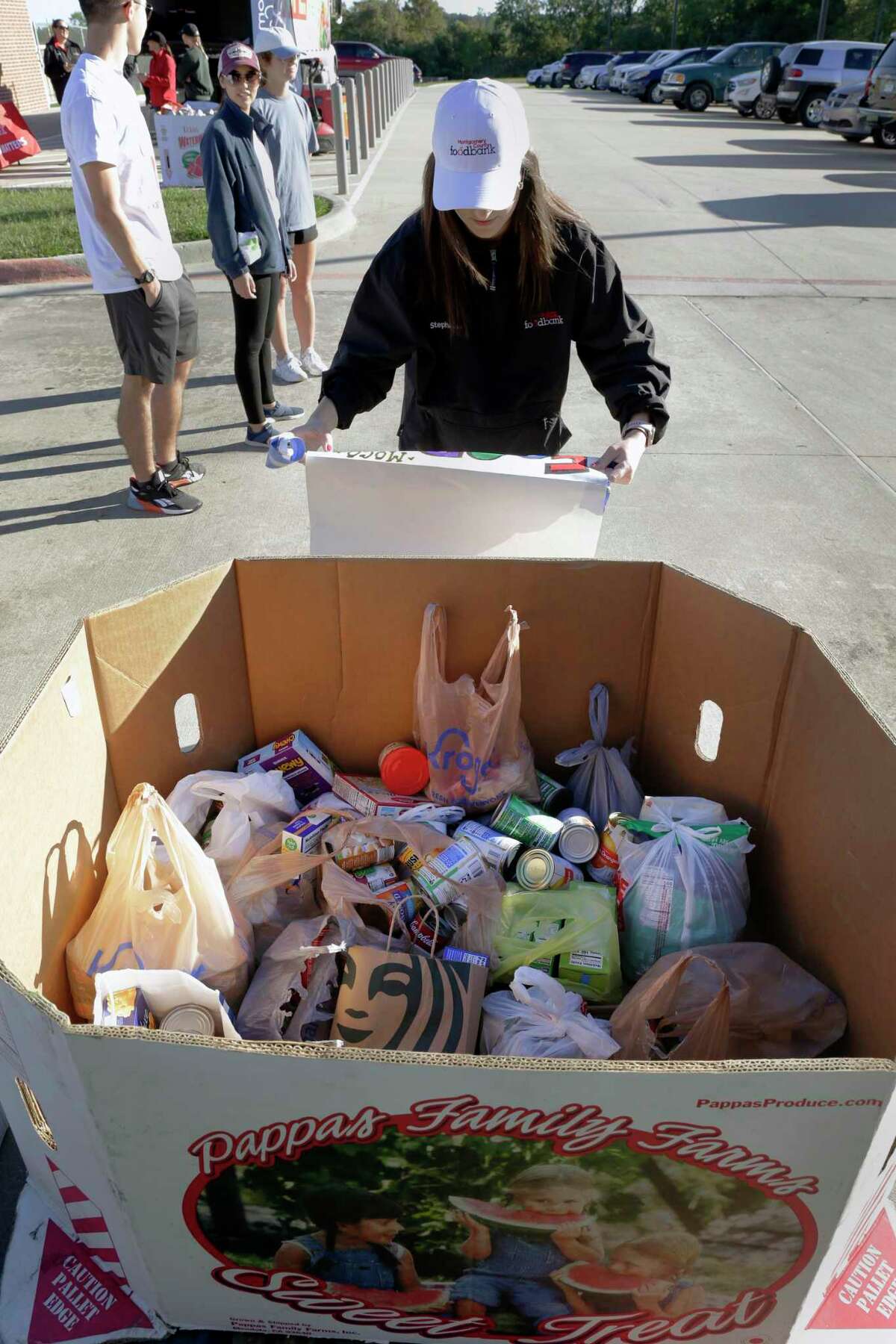 Stephanie Arend, with the Montgomery County Food Bank, tapes signs onto food donation bins for participant drop offs during the first Montgomery ISD Walkathon for Hunger held at the Montgomery Jr. High School track Saturday, Oct. 16, 2021 in Montgomery, TX.