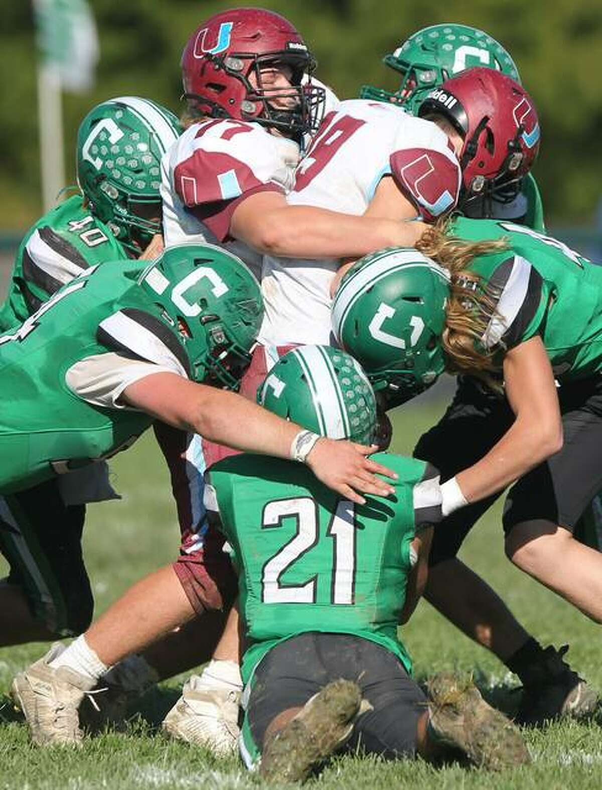 A host of Carrollton Hawks, including Harley Angel (44) converge on Mendon Unity’s Cecil Hunt (19) and Ethan Voss (77) Saturday in Carrollton.
