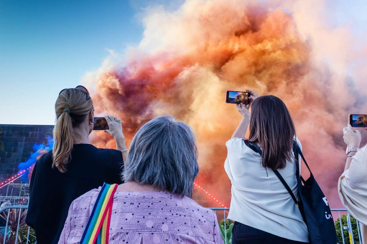 Viewers capture one of the many colorful and smoky moments in Judy Chicago's Forever de Young installation on October 16, 2021. (Kevin Kelleher / Special to SFGATE)