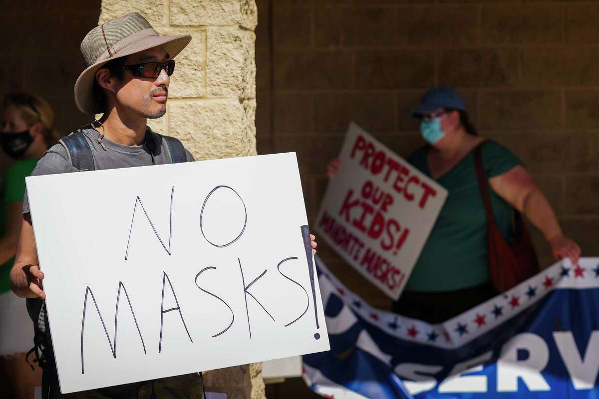Opponents (left) and supporters (right) of mask mandates wait to enter the Carroll ISD school board meeting on Monday, Aug. 23, 2021, in Southlake, Texas. The man at left declined to give his name. (Smiley N. Pool/The Dallas Morning News)