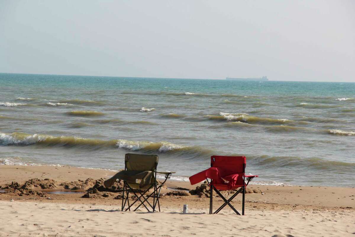 Two empty fold-out chairs on the beach of Wagener County Park watch as a freighter travels on Lake Huron. This is the last weekend the majority of Huron County's parks will be open, with total attendance projected to be at record levels. (Robert Creenan/Huron Daily Tribune)