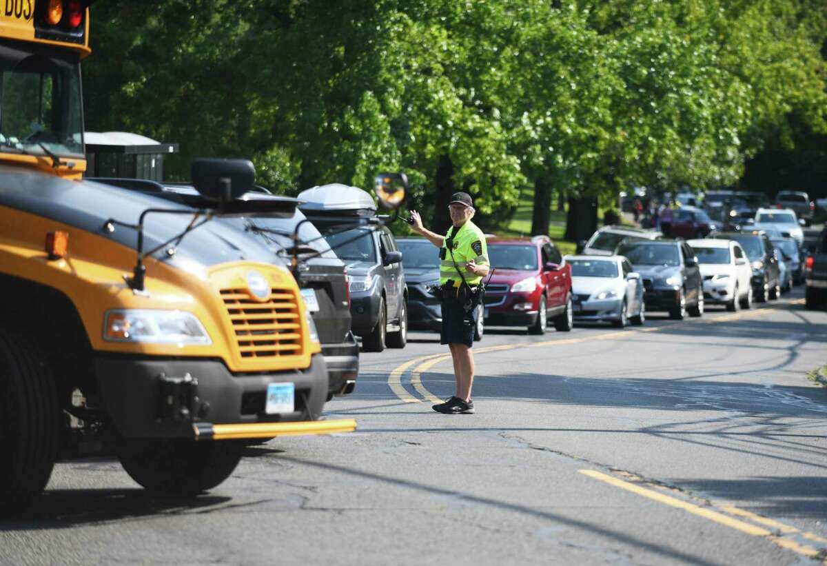 A police officer directs traffic as buses pick up students during dismissal at Brien McMahon High School in Norwalk, Conn. Monday, Sept. 13, 2021. Norwalk Public Schools increased the police presence across the district on Oct. 18 following the report of a threatening message found at the high school over the weekend.