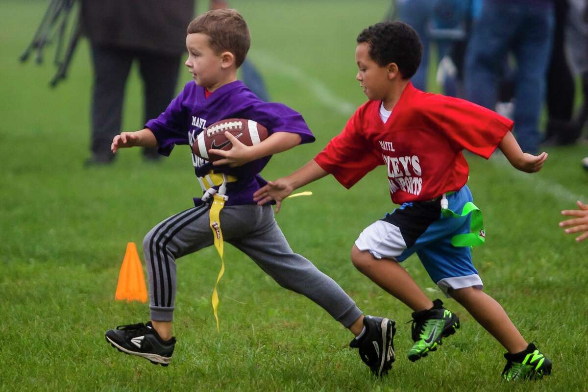 Woodcrest Elementary's Gionni Roberts, 7, carries the ball as he is chased by Central Park Elementary's Kai Jones, 6, during their Midland Area Youth Football League game Saturday, Oct. 9, 2021 at H. H. Dow High School. (Katy Kildee/kkildee@mdn.net)