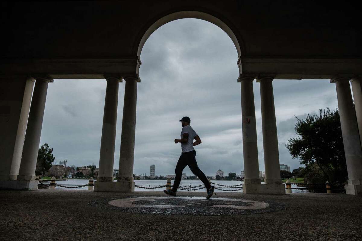 A jogger runs along Lake Merritt under cloudy skies in Oakland. An atmospheric river could form over the Bay Area in the coming days, bringing a torrent of rain with it.